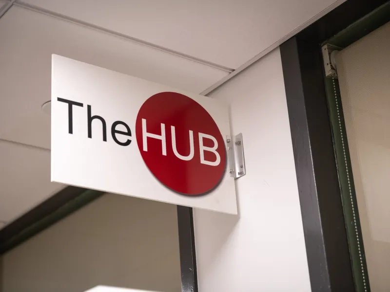 White sign on a cream colored wall containing a red circle with the word Hub inside.