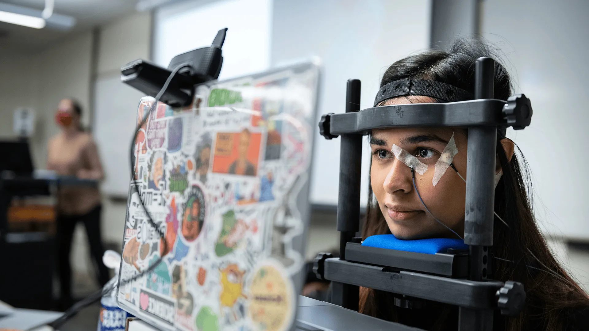 Student with a device on her head in a neuroscience lab looking at a computer