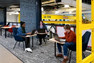 Three people sitting near each other at desks with laptops