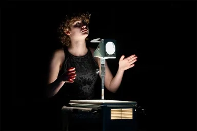 CMU student at an opera dress rehearsal, dramatically lit from a projector.
