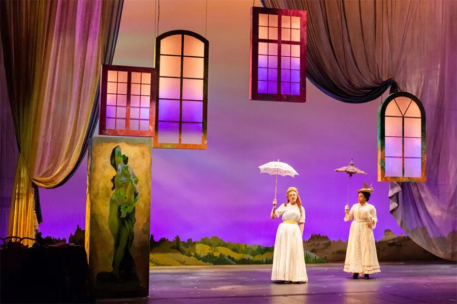 Two women on stage, holding parasols, surrounded by surreal floating windows.
