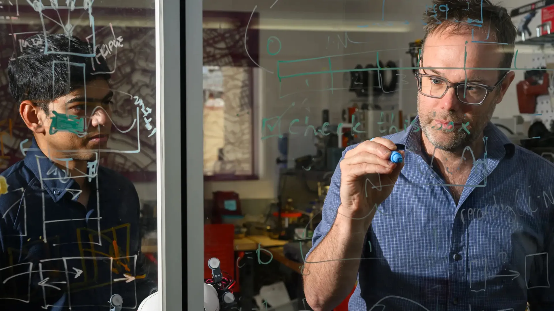 People working on a white board in a technical space